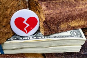broken heart pin on top of stack of money
